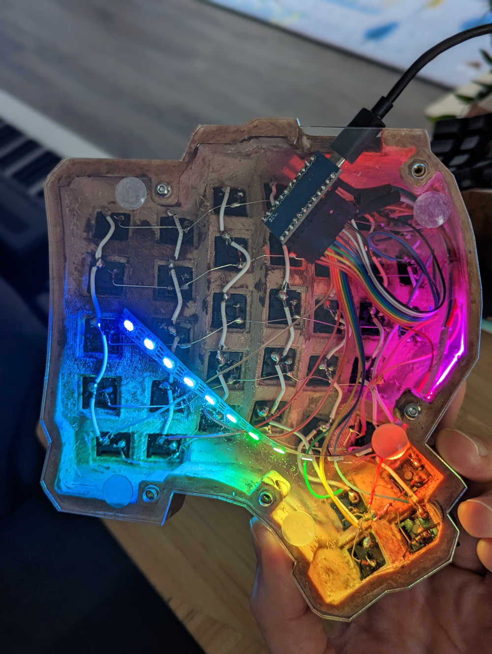 A keyboard half with a LED strip lit in rainbow colors